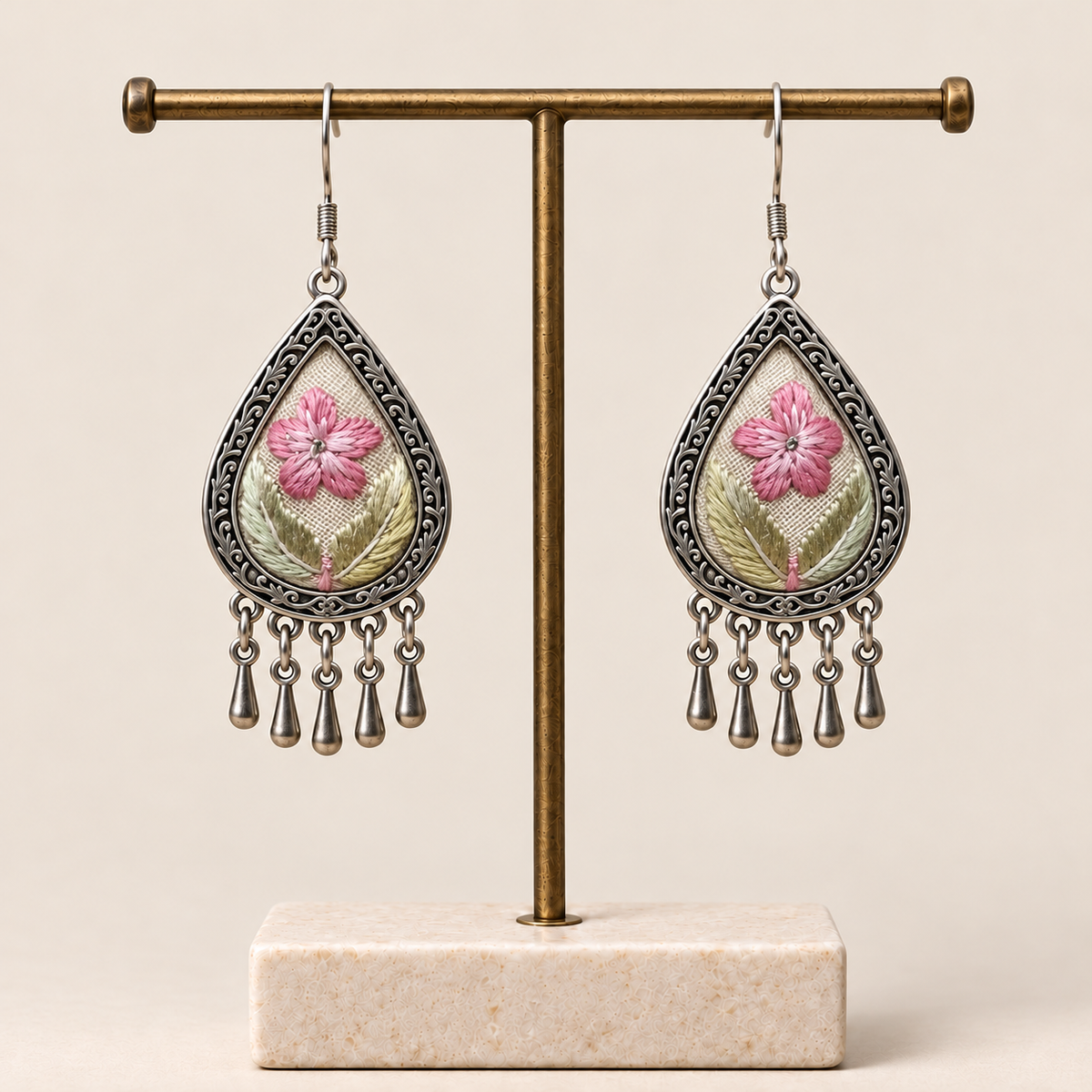 Blush Reverie floral teardrop earrings hanging from a T-bar stand with five short drops beneath each earring.