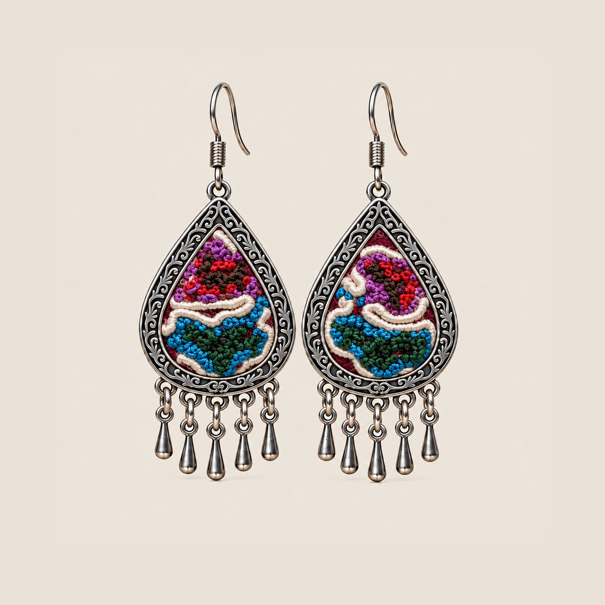 Prismatic Reverie teardrop earrings with red, purple, blue and green knotted embroidery, ivory curves and five short drops.