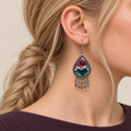 Close-up of a worn Prismatic Reverie earring showing colorful raised knots, ivory threads and five short drops.