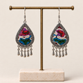 Prismatic Reverie knotted embroidery earrings hanging from a T-bar stand, with five short drops beneath each teardrop.