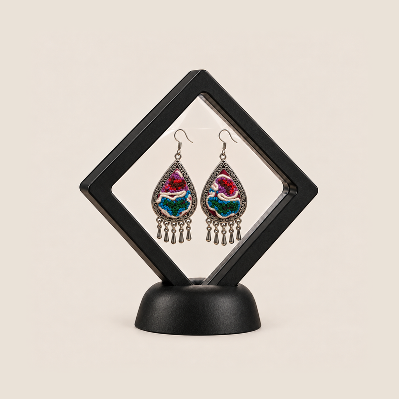 Prismatic Reverie earrings displayed inside a clear diamond-shaped frame with a black border and base.
