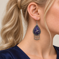 Close-up of a worn Violet Arabesque earring showing silver-white floral outlines on purple embroidery and five short drops.