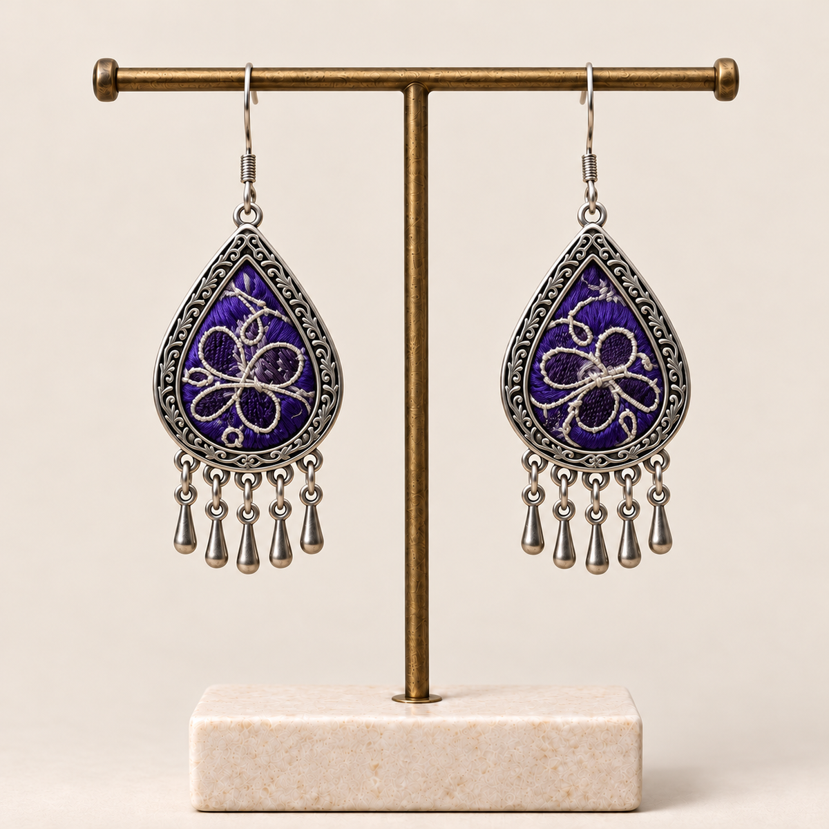 Violet Arabesque Panjin embroidery earrings hanging from a T-bar stand with five short drops beneath each teardrop.