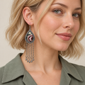 Model wearing a Burgundy Nocturne earring with burgundy and ivory floral embroidery above five long chains with teardrop ends.