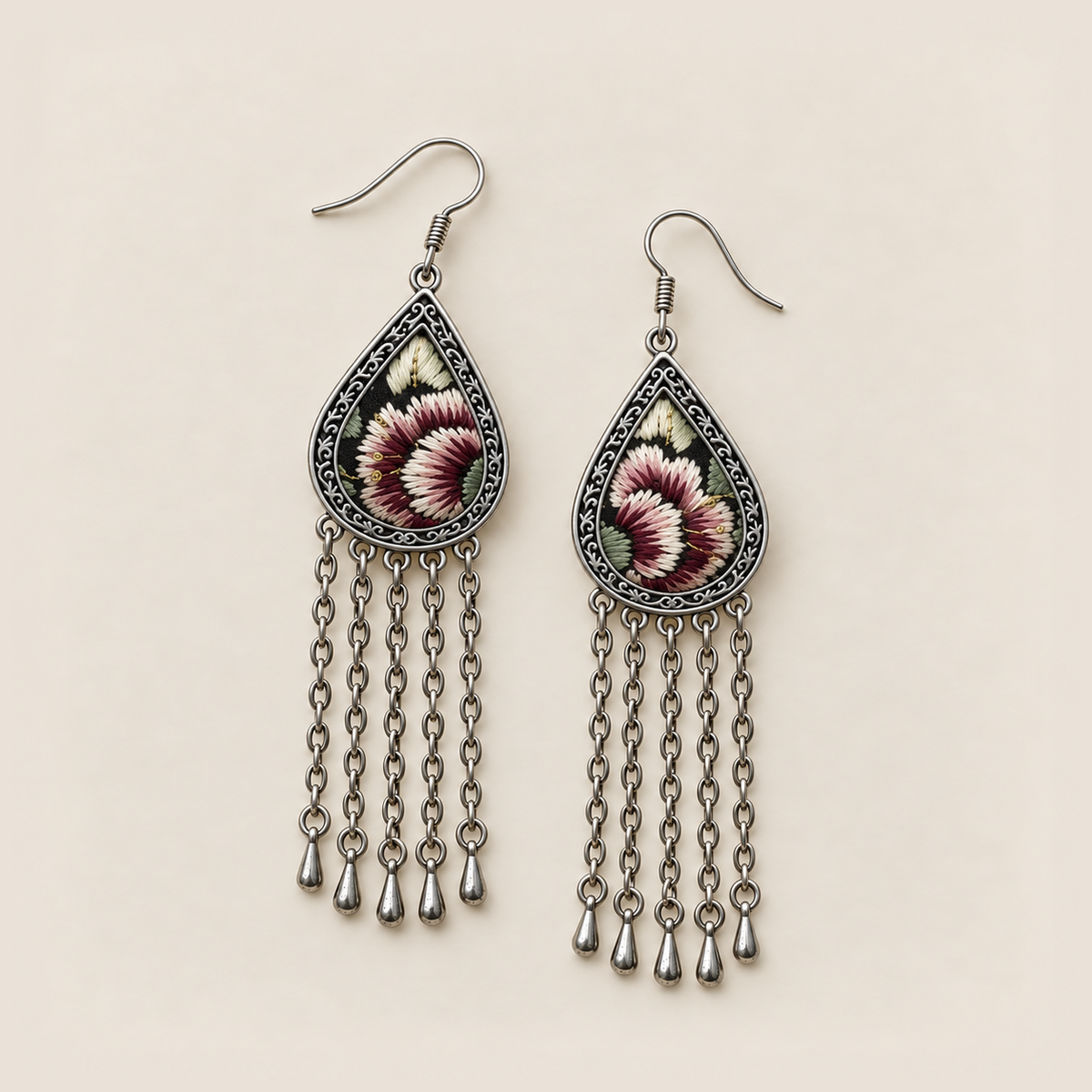 Burgundy Nocturne earrings lying face up, showing differing floral embroidery sections and pale green leaves on black.