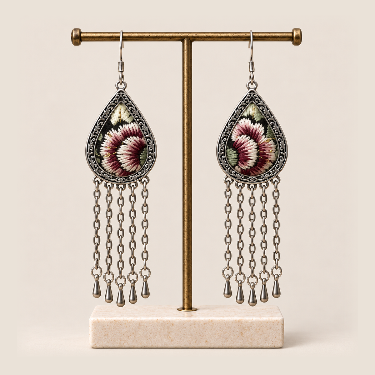 Burgundy Nocturne floral earrings hanging from a T-bar stand with five long chains and teardrop ends beneath each frame.