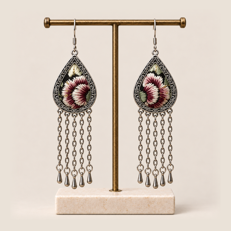 Burgundy Nocturne floral earrings hanging from a T-bar stand with five long chains and teardrop ends beneath each frame.