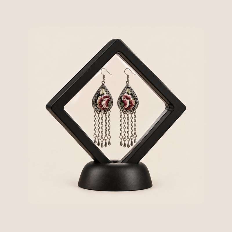 Burgundy Nocturne long tassel earrings displayed inside a clear diamond-shaped frame with a black border and base.