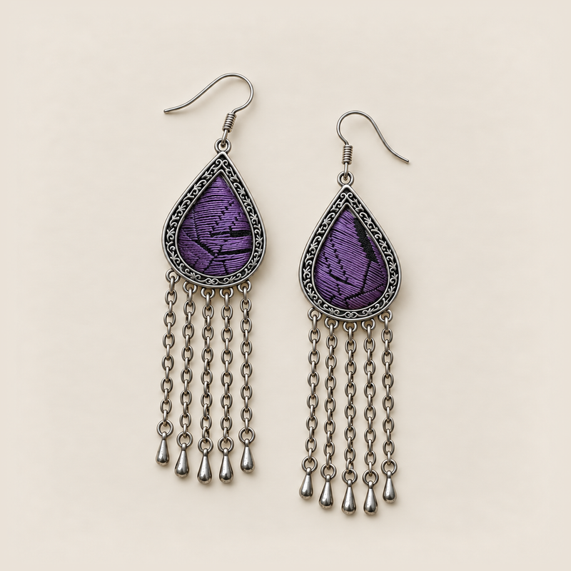 Amethyst Cadence earrings lying face up, showing different black geometric patterns among parallel purple stitches.