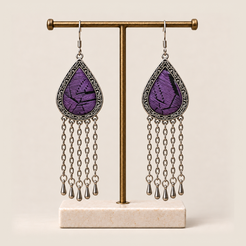 Amethyst Cadence earrings hanging from a T-bar stand with five long chains and teardrop ends beneath each embroidered frame.