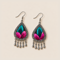 Fuchsia Tide earrings lying face up, showing differences between the teal and pink embroidered sections across the pair.