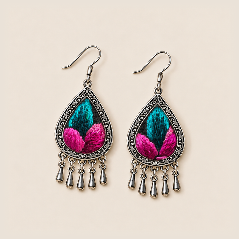 Fuchsia Tide earrings lying face up, showing differences between the teal and pink embroidered sections across the pair.