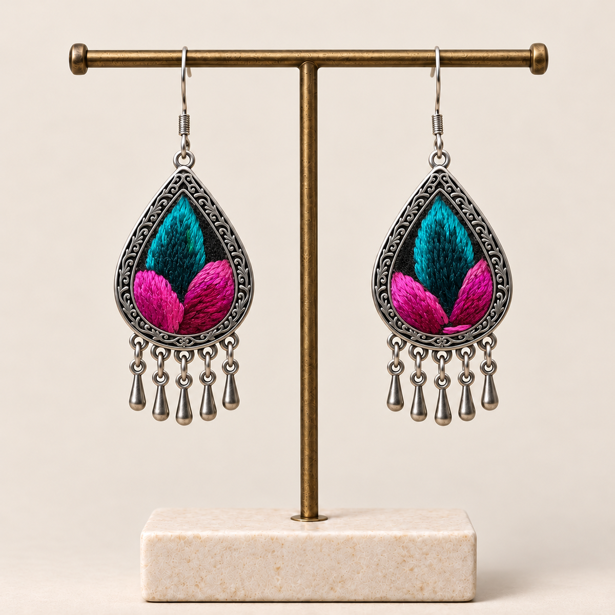 Fuchsia Tide Songtao embroidery earrings hanging from a T-bar stand with five short drops beneath each teardrop.