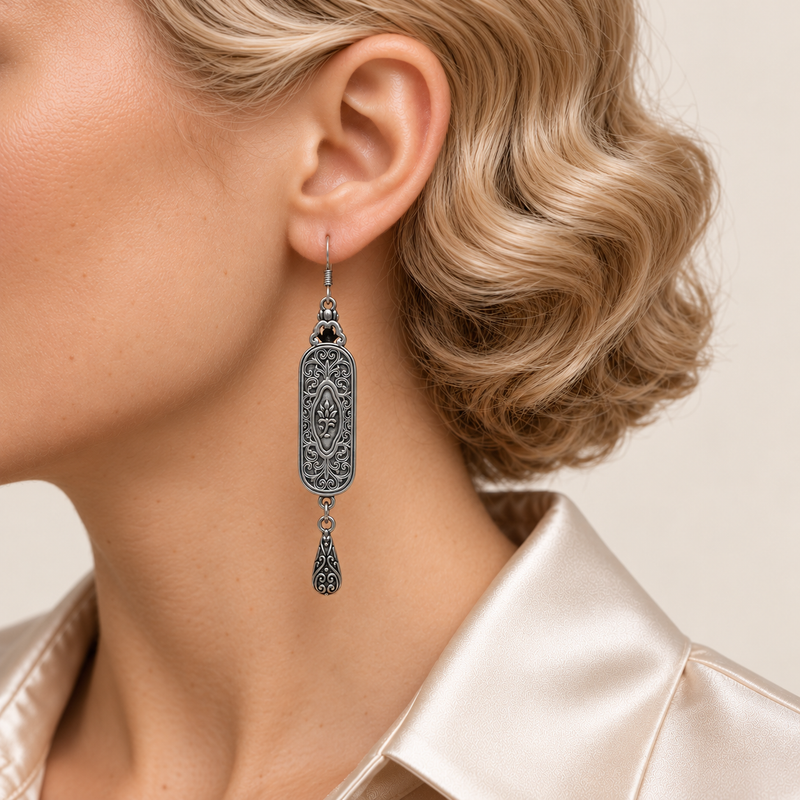 Close-up of an Indigo Stillness earring worn with its scrollwork reverse and central oval motif facing outward.