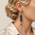 Close-up of an Indigo Stillness earring worn with its pale batik curves and single engraved teardrop facing forward.