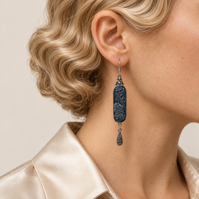 Close-up of an Indigo Stillness earring worn with its pale batik curves and single engraved teardrop facing forward.