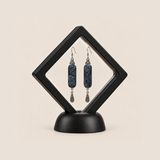 Indigo Stillness batik earrings presented inside a black diamond-shaped display frame.