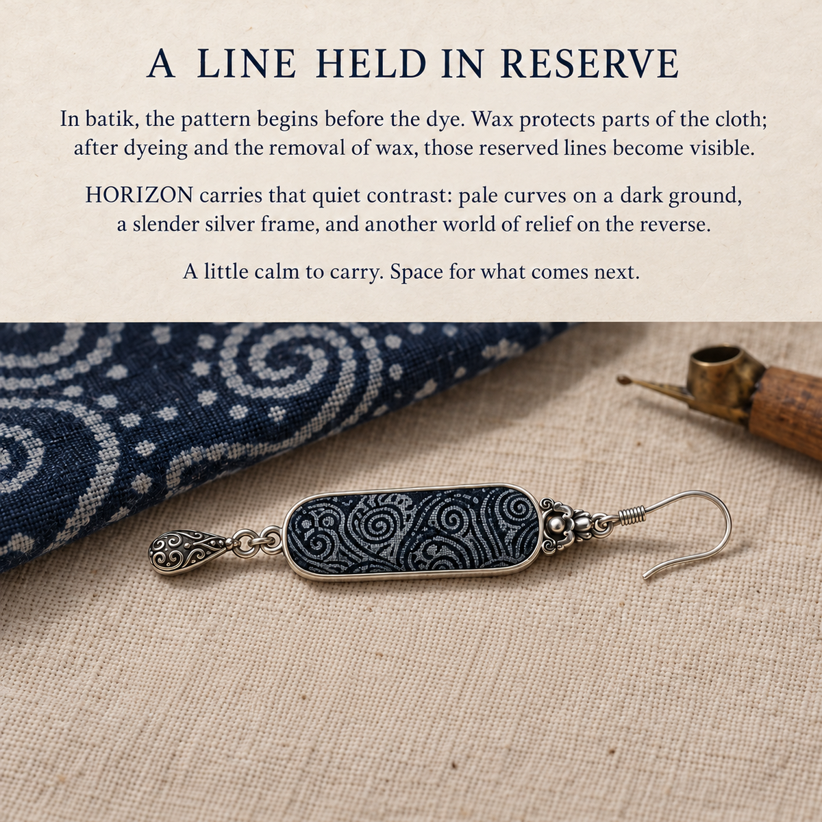 Batik story card with an Indigo Stillness earring on fabric beside patterned cloth and a wax tool.