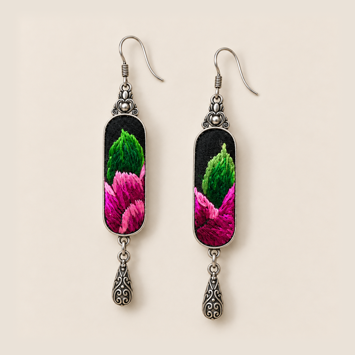 Front close-up of Verdant Blush earrings, showing different green and pink stitched sections on black textile panels.