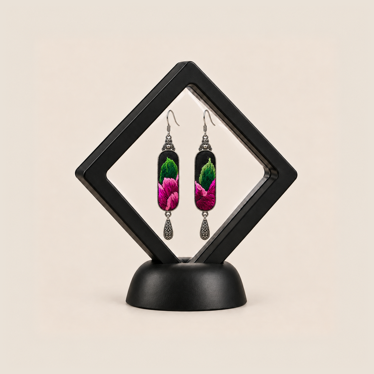 Verdant Blush embroidered earrings presented in a black diamond-shaped display frame on a matching base.