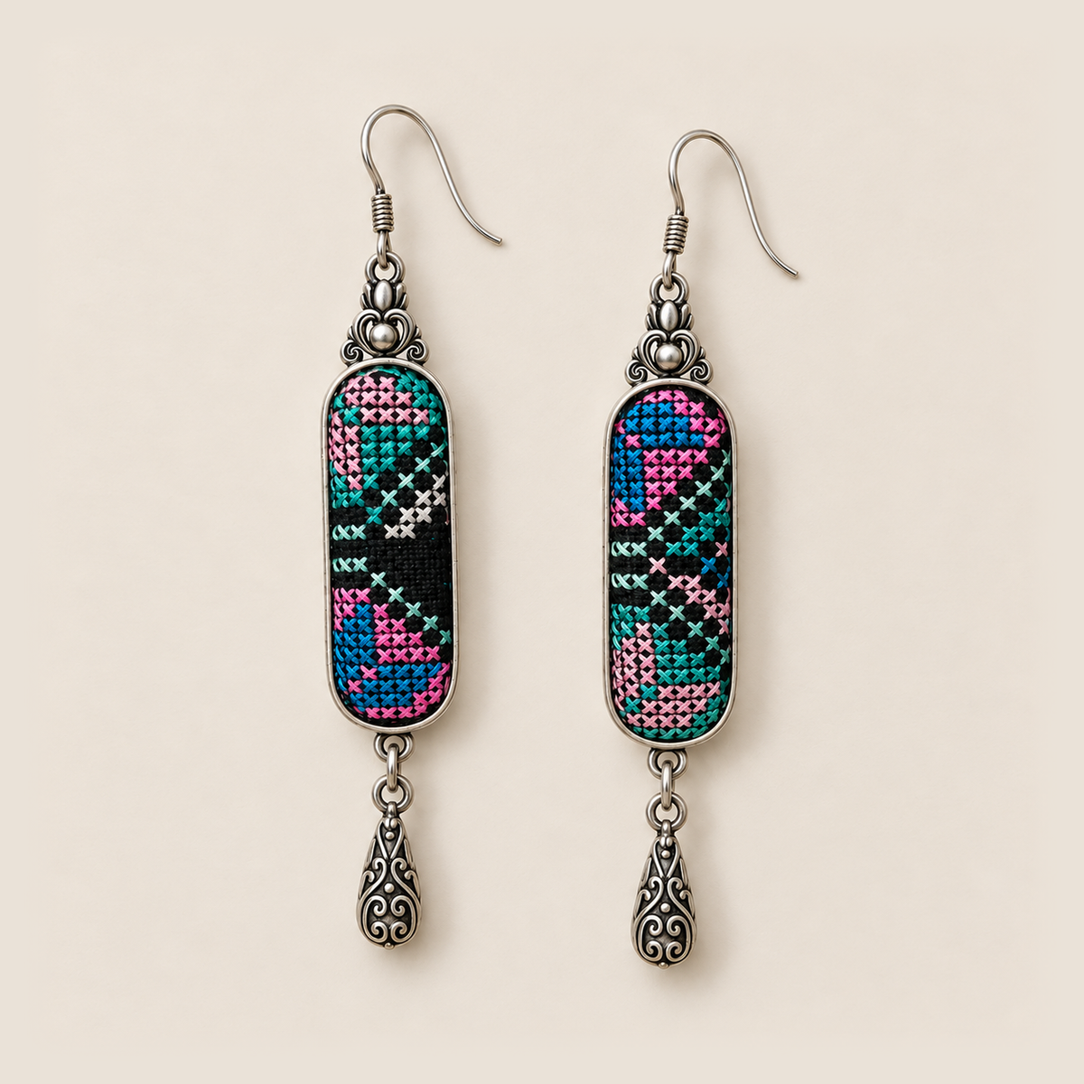 Front detail of Pastel Cadence earrings with different pink, teal, blue and pale counted-thread patterns on black textile.
