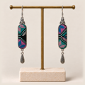 Pastel Cadence embroidered earrings hanging from a gold-tone display stand with a pale rectangular base.