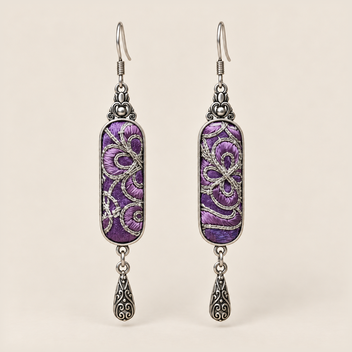 Violet Luminance Panjin Embroidery earrings featuring purple stitching with pale looping outlines, with one engraved teardrop each.
