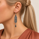 Violet Luminance earring worn with its scrollwork reverse and central oval motif facing outward above one teardrop.