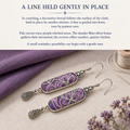 Couching story card with Violet Luminance earrings beside purple cloth, a pale thread spool, a needle and dried flowers.