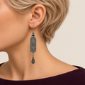 Petal Nocturne earring worn with its scrollwork reverse and central oval motif facing outward above one teardrop.