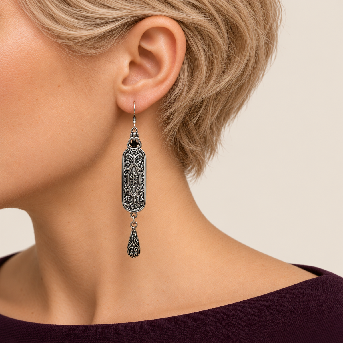 Petal Nocturne earring worn with its scrollwork reverse and central oval motif facing outward above one teardrop.