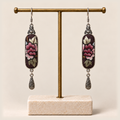 Petal Nocturne embroidered earrings hanging from a gold-tone display stand with a pale rectangular base.