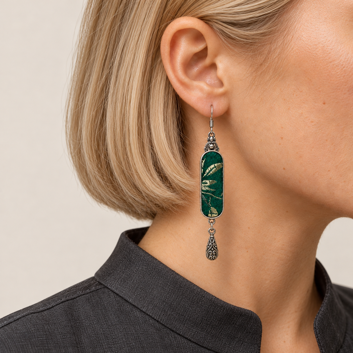 Emerald Reverie earring worn with pale leaf-like motifs on green Song Brocade facing forward above a single teardrop.