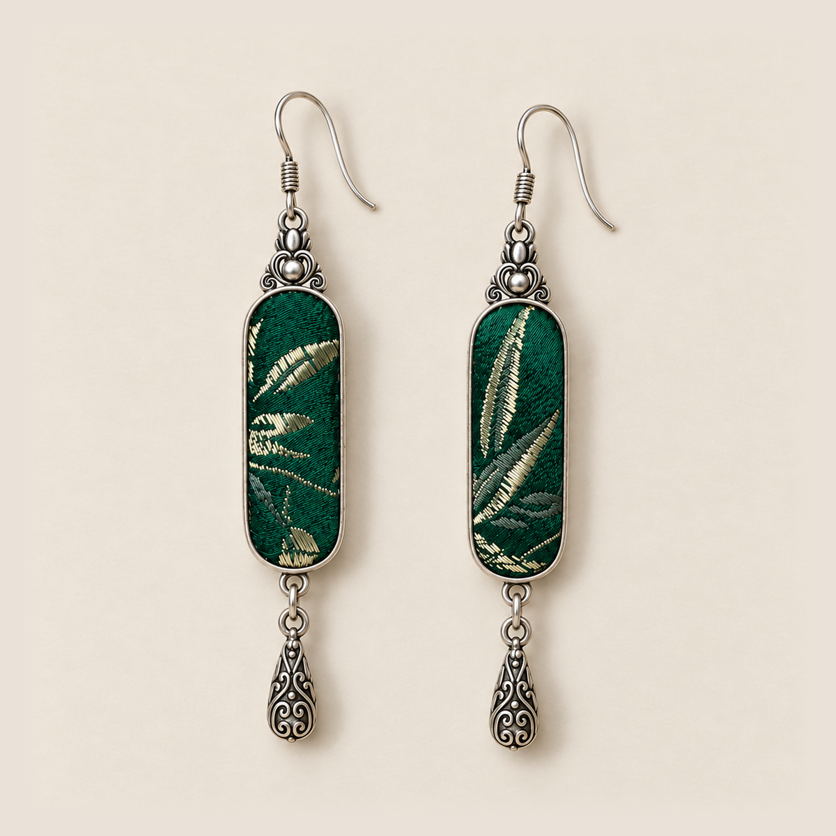 Front detail of Emerald Reverie earrings showing different pale leaf-like patterns woven into green textile panels.
