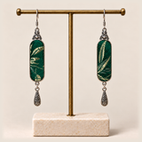 Emerald Reverie Song Brocade earrings hanging from a gold-tone display stand with a pale rectangular base.