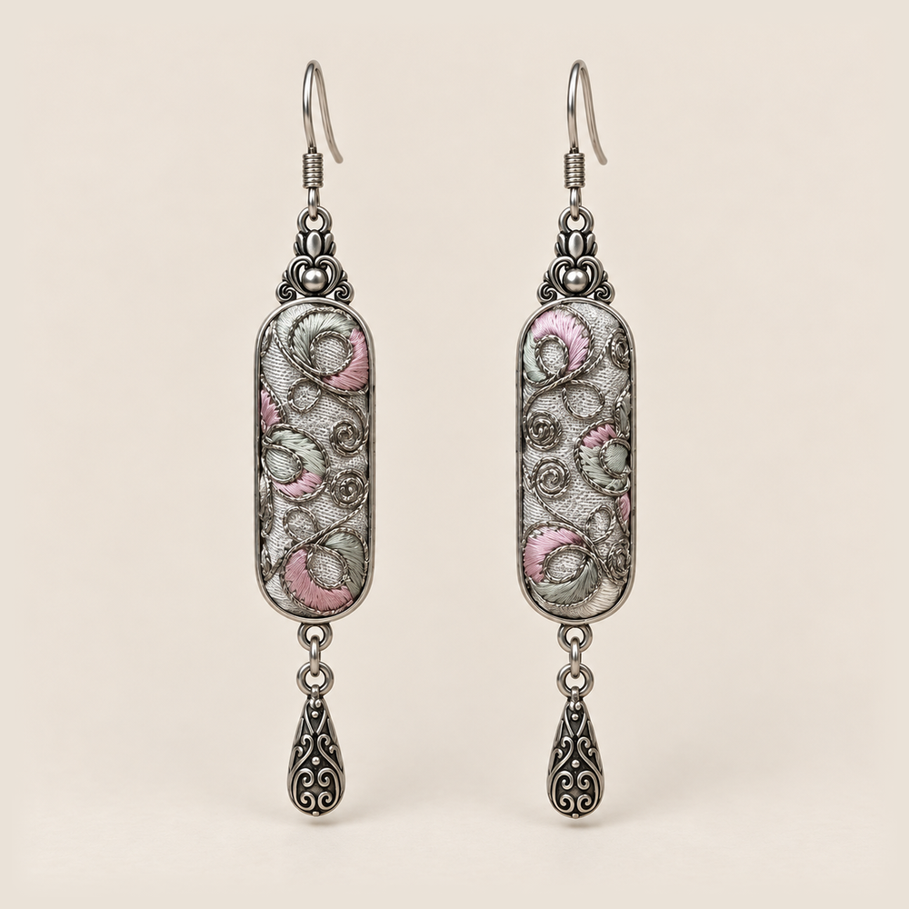 Pastel Arabesque Panjin Embroidery earrings with pale pink and green fills, looping outlines on light gray textile and one teardrop each.