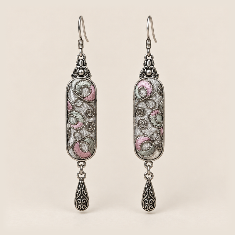 Pastel Arabesque Panjin Embroidery earrings with pale pink and green fills, looping outlines on light gray textile and one teardrop each.