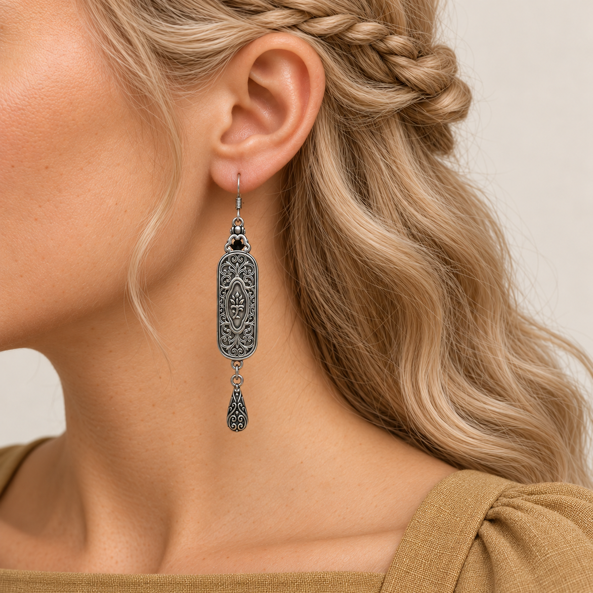 Pastel Arabesque earring worn with its scrollwork reverse and central oval motif facing outward above one engraved teardrop.
