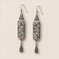 Front detail of Pastel Arabesque earrings showing different pink and green filled curves and coiled outlines on light gray textile.