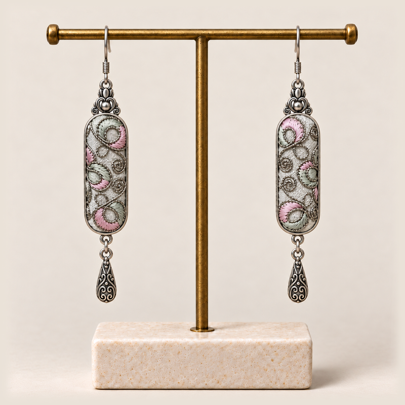 Pastel Arabesque earrings hanging from a gold-tone display stand with a pale rectangular base.