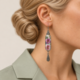 Close-up of a Blossom Serenade earring worn with pink and white embroidered flowers and green leaves facing outward.