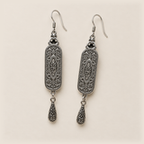 Reverse of the Blossom Serenade pair, showing curled metal relief, central oval motifs and one engraved teardrop per earring.