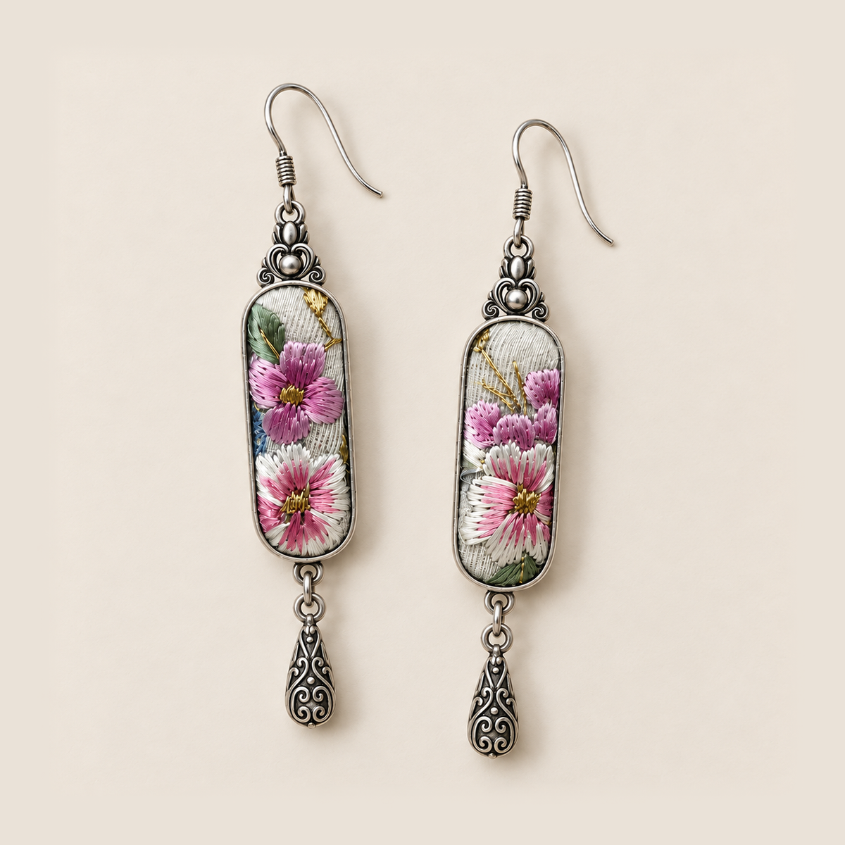 Blossom Serenade earrings laid on a pale surface, showing different floral details across the two embroidered panels.