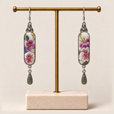 Blossom Serenade floral earrings hanging from a gold-toned display stand with a pale rectangular base.