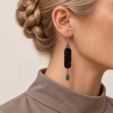 Close-up of an Ember Constellation earring worn with sparse colored stitches on its black front panel.
