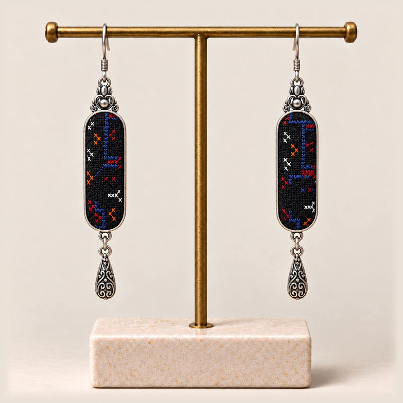 Ember Constellation earrings hanging from a gold-toned display stand with a pale rectangular base.
