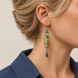Close-up of an Autumn Sonata earring worn with yellow-green leaves and pale-outlined ochre petals facing outward.