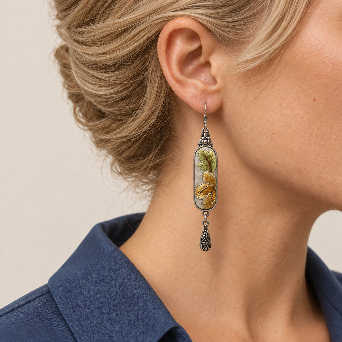 Close-up of an Autumn Sonata earring worn with yellow-green leaves and pale-outlined ochre petals facing outward.