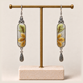 Autumn Sonata earrings hanging from a gold-toned display stand with a pale rectangular base.