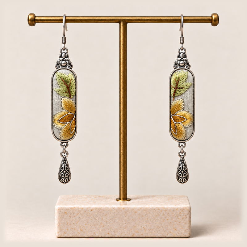 Autumn Sonata earrings hanging from a gold-toned display stand with a pale rectangular base.